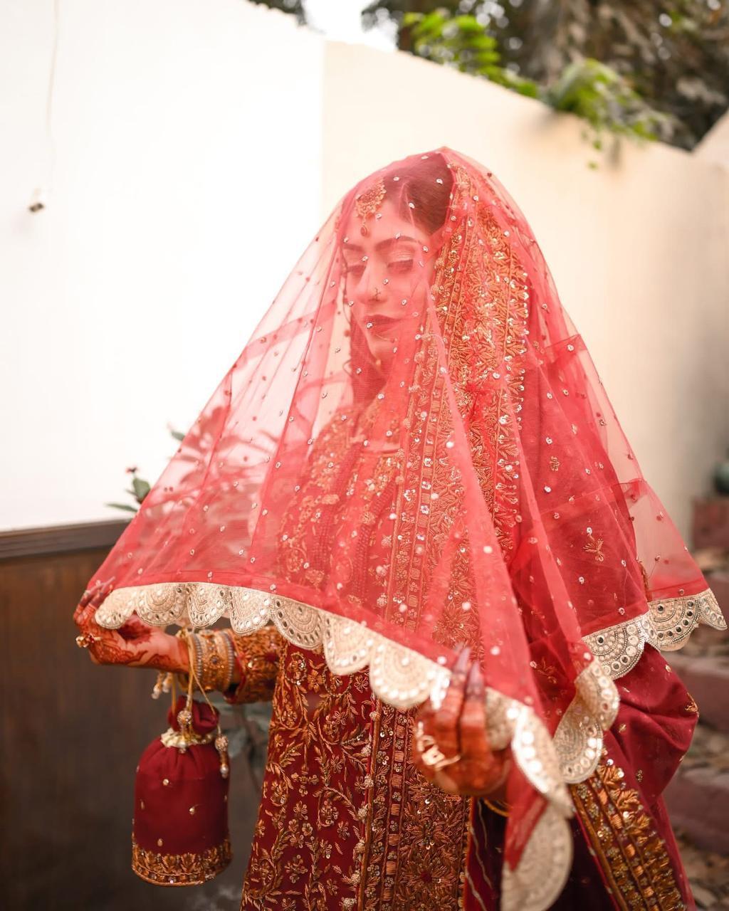 Red bridal veil with gold embellished scalloped border and delicate detailing for a traditional South Asian wedding.