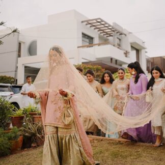 Soft ivory Pakistani bridal dupatta veil with delicate embellishments and long flowing drape styled with a traditional South Asian wedding outfit.