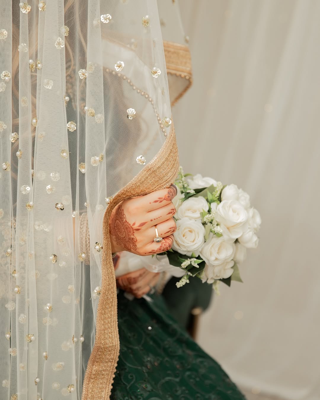 Ivory bridal veil with pearl and sequin embellishments and an elegant gold border for a traditional South Asian wedding.