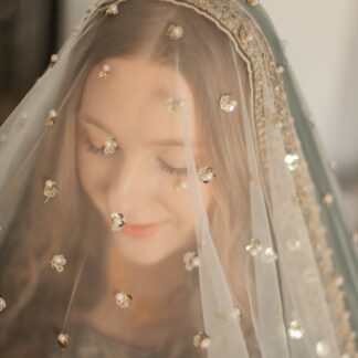 Ivory bridal veil with pearl and sequin embellishments and an elegant gold border for a traditional South Asian wedding.