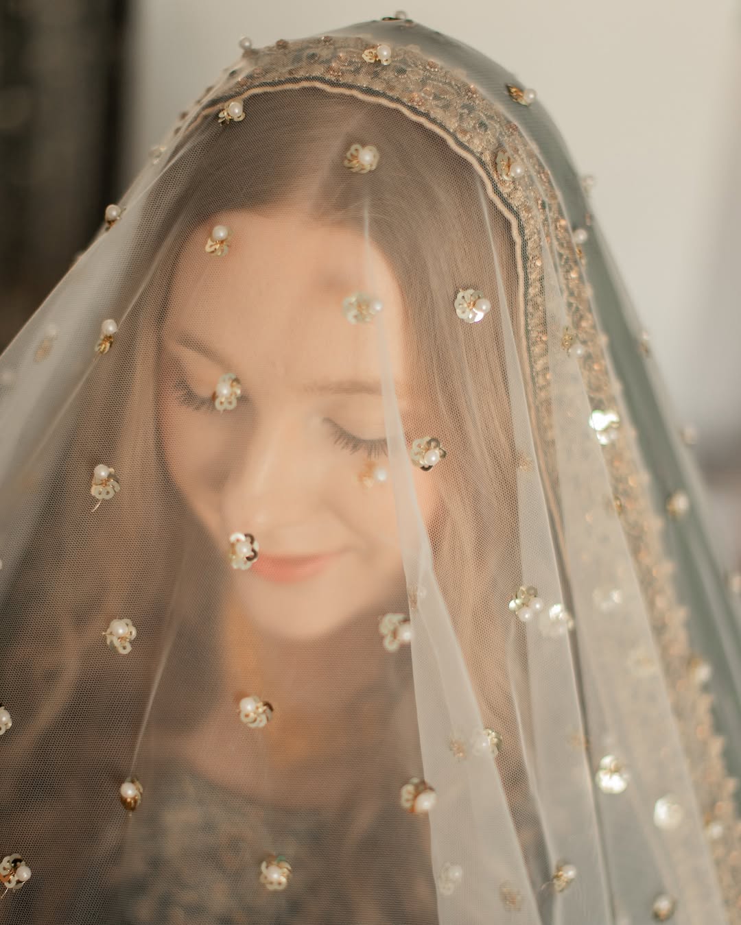 Ivory bridal veil with pearl and sequin embellishments and an elegant gold border for a traditional South Asian wedding.