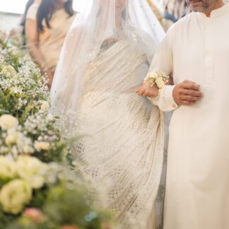 White Pakistani Nikkah dupatta veil with delicate silver detailing and statement border worn by a bride during the Nikkah signing ceremony.