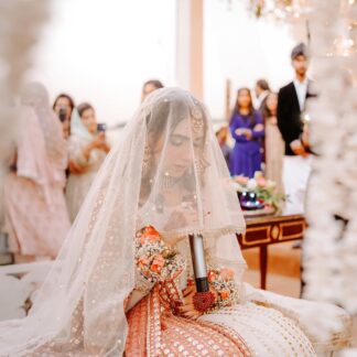 White Pakistani Nikkah dupatta veil with delicate gold detailing and elegant border styled over the head for a traditional Muslim wedding ceremony.