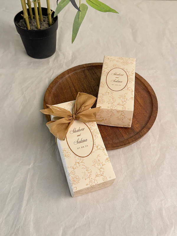 Ivory rectangular Nikkah favor box with delicate gold floral design, personalized couple details and satin ribbon for Pakistani weddings.