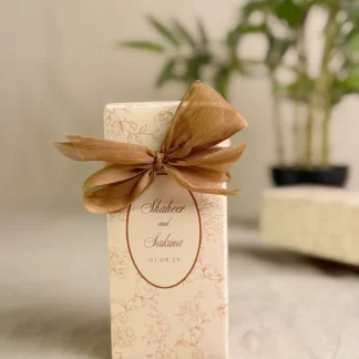 Ivory rectangular Nikkah favor box with delicate gold floral design, personalized couple details and satin ribbon for Pakistani weddings.