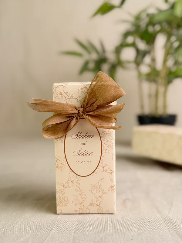 Ivory rectangular Nikkah favor box with delicate gold floral design, personalized couple details and satin ribbon for Pakistani weddings.