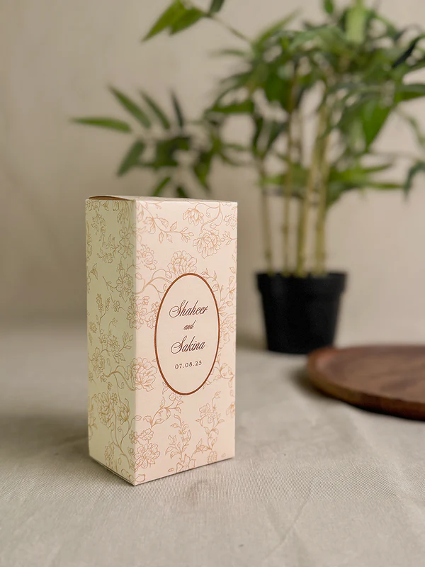 Ivory rectangular Nikkah favor box with delicate gold floral design, personalized couple details and satin ribbon for Pakistani weddings.