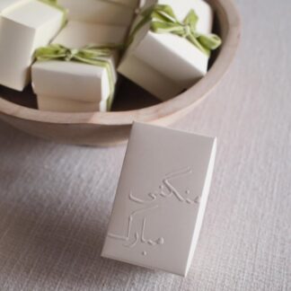 Ivory embossed Mangni Mubarak favor boxes with sage green velvet ribbons for Pakistani engagement sweets and guest favors.