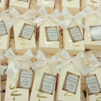 Personalized white Nikkah favor boxes with Nikkah Mubarak detailing, custom couple name tags and elegant white ribbon for a Muslim wedding celebration.