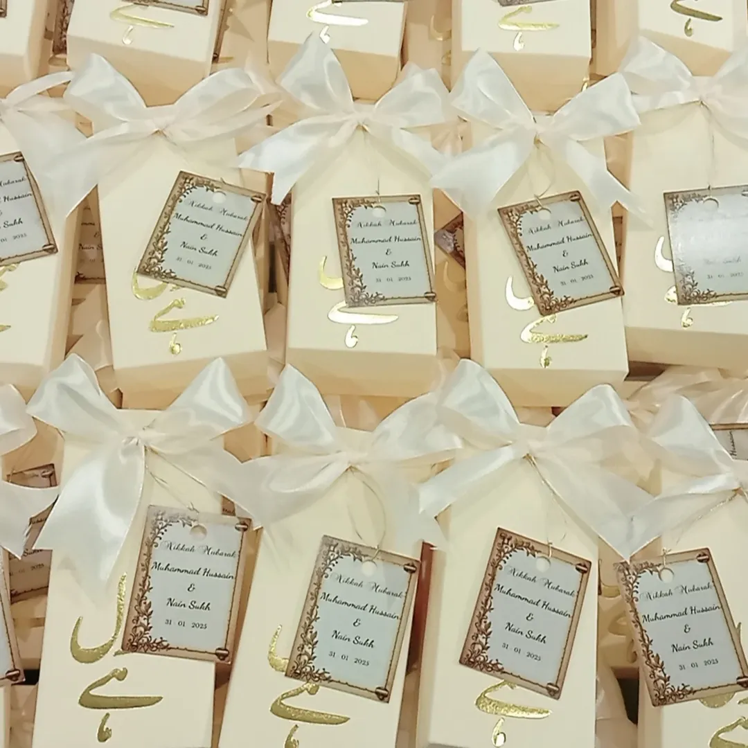 Personalized white Nikkah favor boxes with Nikkah Mubarak detailing, custom couple name tags and elegant white ribbon for a Muslim wedding celebration.