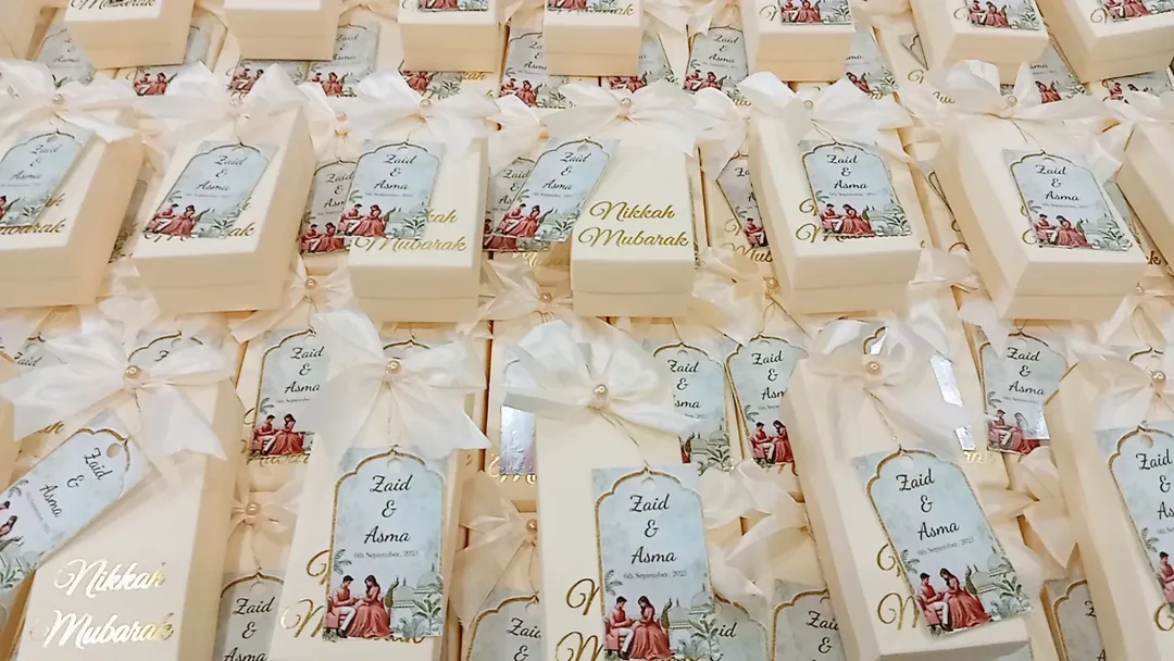 Personalized white Nikkah favor boxes with Nikkah Mubarak detailing, custom couple name tags and elegant white ribbon for a Muslim wedding celebration.