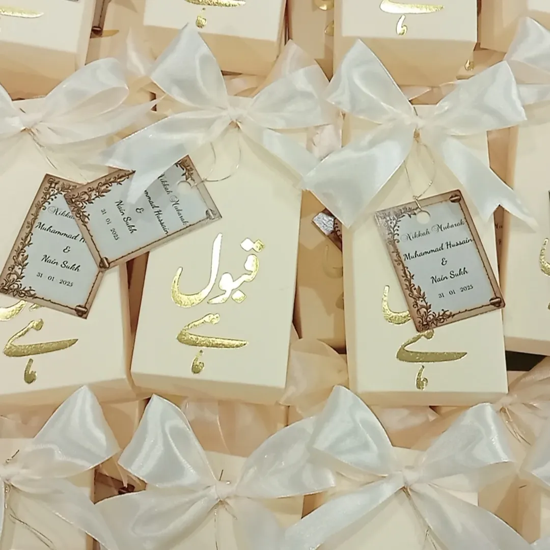 Personalized white Nikkah favor boxes with Nikkah Mubarak detailing, custom couple name tags and elegant white ribbon for a Muslim wedding celebration.