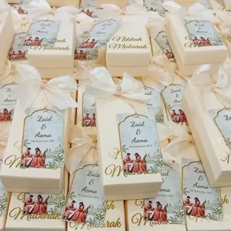Personalized white Nikkah favor boxes with Nikkah Mubarak detailing, custom couple name tags and elegant white ribbon for a Muslim wedding celebration.