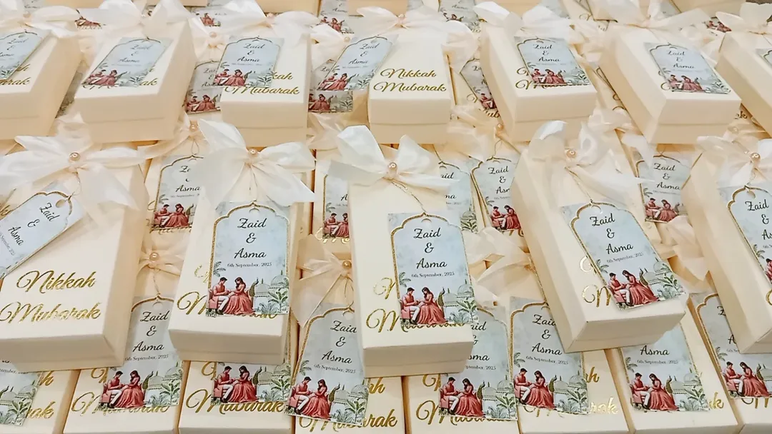 Personalized white Nikkah favor boxes with Nikkah Mubarak detailing, custom couple name tags and elegant white ribbon for a Muslim wedding celebration.