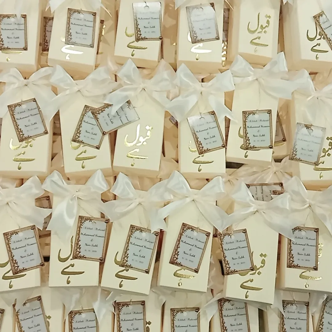 Personalized white Nikkah favor boxes with Nikkah Mubarak detailing, custom couple name tags and elegant white ribbon for a Muslim wedding celebration.