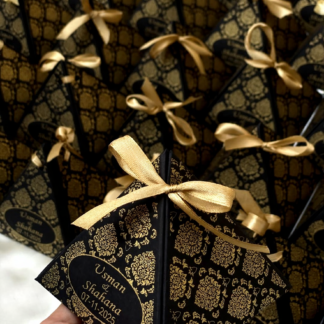Black and gold personalized pyramid favor boxes with ornate detailing and gold ribbon bows for weddings, Nikkah ceremonies and special events.