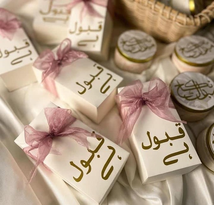 White Qabool Hai favor boxes with gold lettering and blush pink organza ribbon bows for Nikkah ceremonies, Muslim weddings and Pakistani wedding celebrations.