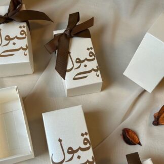 Ivory Qabool Hai favor boxes with Urdu calligraphy and brown ribbon for Pakistani Nikkah and Muslim wedding celebrations.