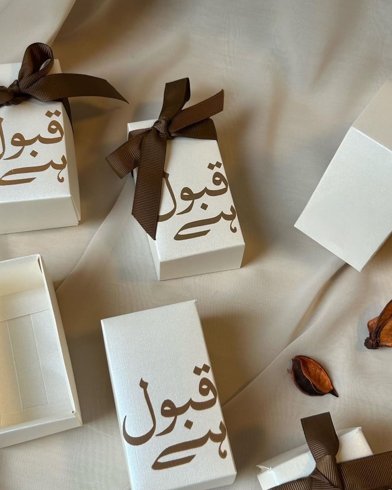 Ivory Qabool Hai favor boxes with Urdu calligraphy and brown ribbon for Pakistani Nikkah and Muslim wedding celebrations.