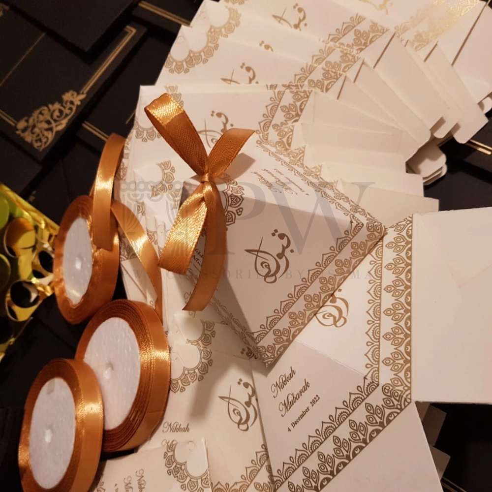 Ivory pyramid Nikkah favor boxes with gold decorative detailing and satin bows for personalized Pakistani and Muslim wedding favors.