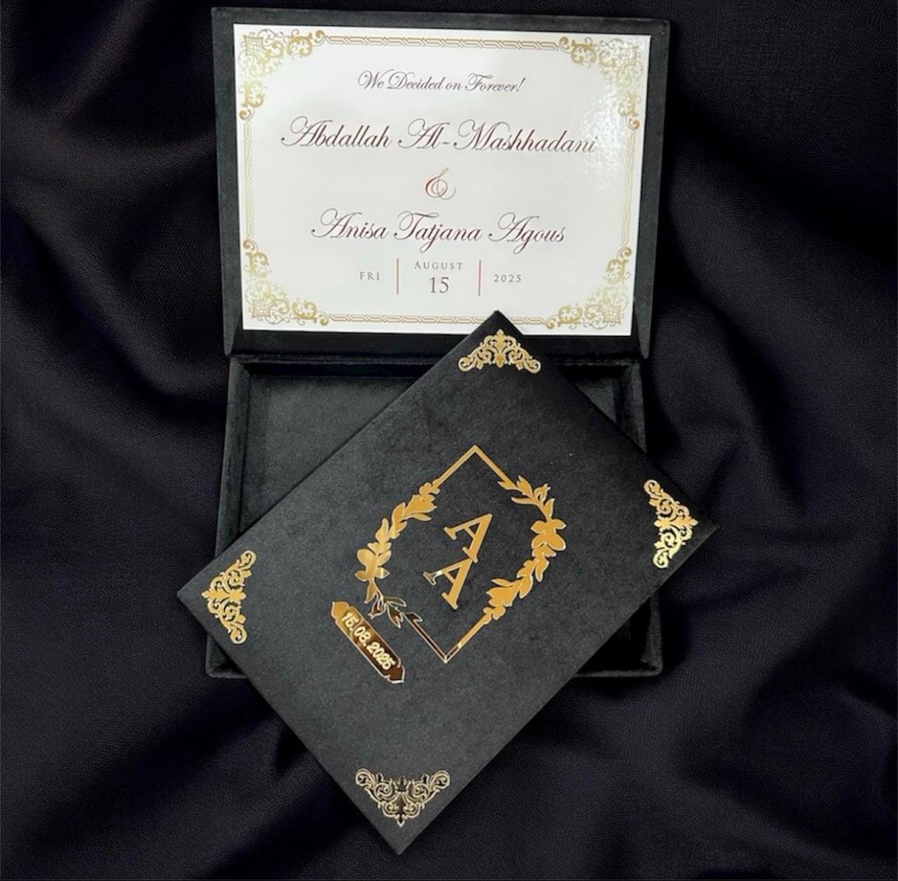 Personalized black Nikkah Nama folder with gold floral monogram, custom wedding date, ornate gold corners, and matching black keepsake box featuring an ivory wedding announcement for Pakistani and Muslim weddings in the USA.