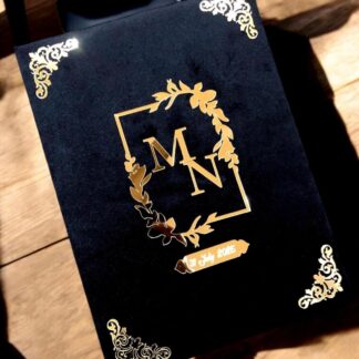 Personalized black Nikkah Nama folder with gold floral monogram, custom wedding date, ornate gold corners, and matching black keepsake box featuring an ivory wedding announcement for Pakistani and Muslim weddings in the USA.
