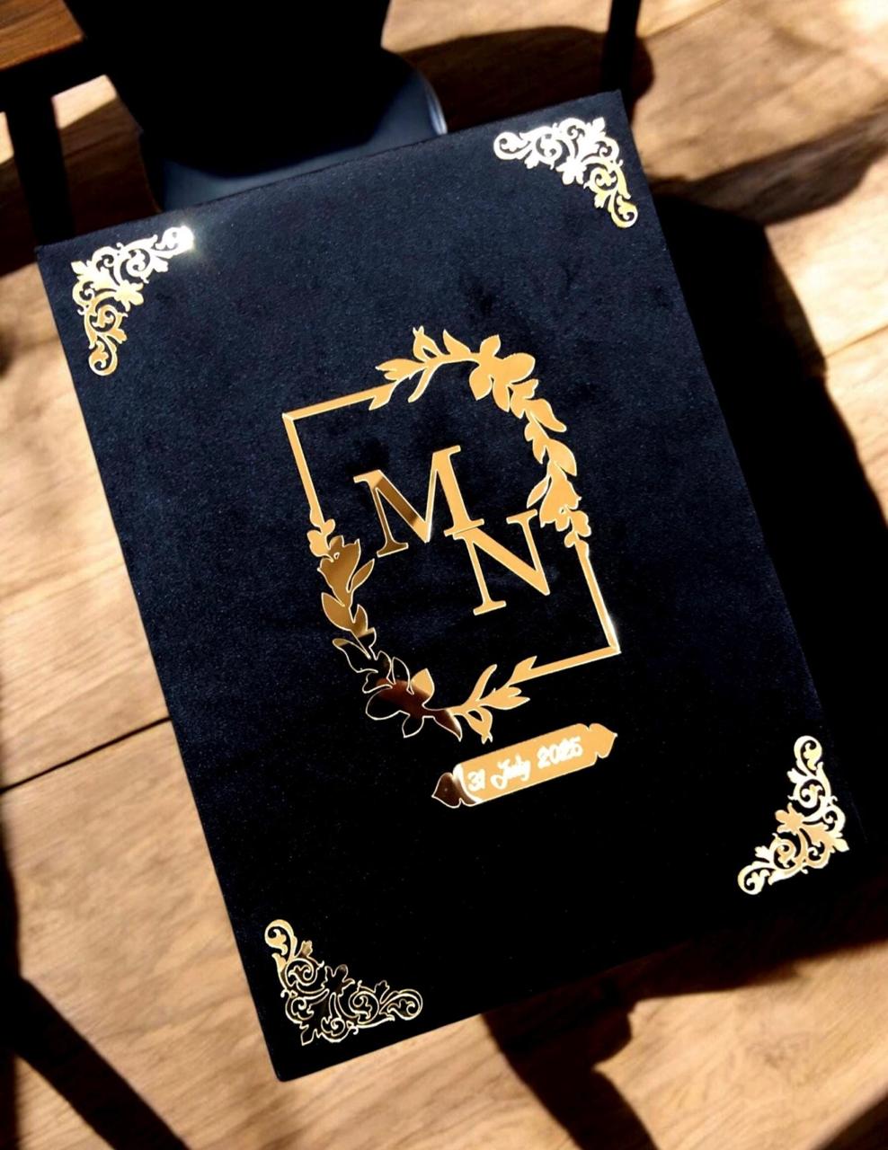 Personalized black Nikkah Nama folder with gold floral monogram, custom wedding date, ornate gold corners, and matching black keepsake box featuring an ivory wedding announcement for Pakistani and Muslim weddings in the USA.