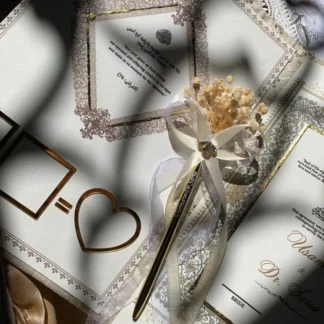Luxury ivory embroidered Nikkah Nama folder with metallic gold calligraphy, ornate corner decorations, and a decorative signing pen, presented in a champagne-gold satin-lined gift box for Pakistani and Muslim wedding ceremonies.