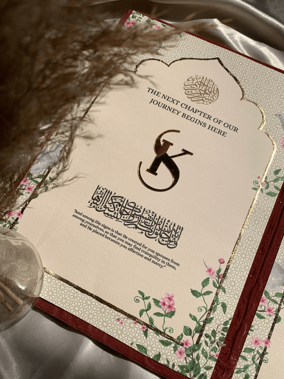 Personalized maroon velvet Nikkah Nama folder featuring metallic gold Urdu calligraphy, intricate ornamental gold corners, custom wedding date plaque, and decorative floral signing pen with pink satin ribbons for Pakistani and Muslim weddings in the USA.