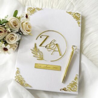 Luxury ivory white personalized Nikkah Nama folder with gold couple's initials monogram, decorative botanical wreath, and elegant velvet-style cover for Pakistani Muslim weddings.
