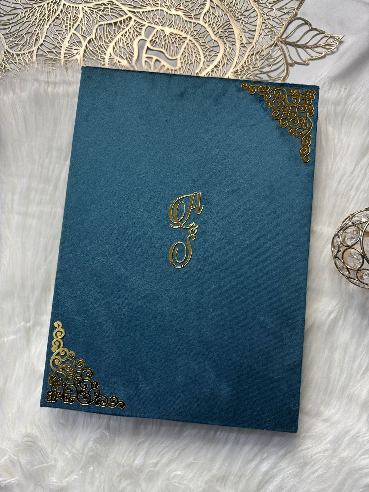 Personalized Nikkah Nama marriage certificate with intricate gold Islamic borders, Arabic calligraphy, and traditional bride-and-groom illustration inside a luxury teal blue folder.