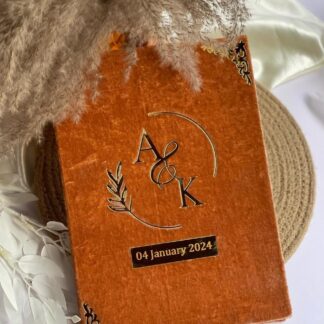 Open personalized Nikkah Nama folder in rust brown velvet-style finish featuring ivory Islamic marriage certificate pages, intricate gold floral borders, custom couple's names, Arabic calligraphy, and a decorative gold signing pen with a red rose for Pakistani Muslim weddings.