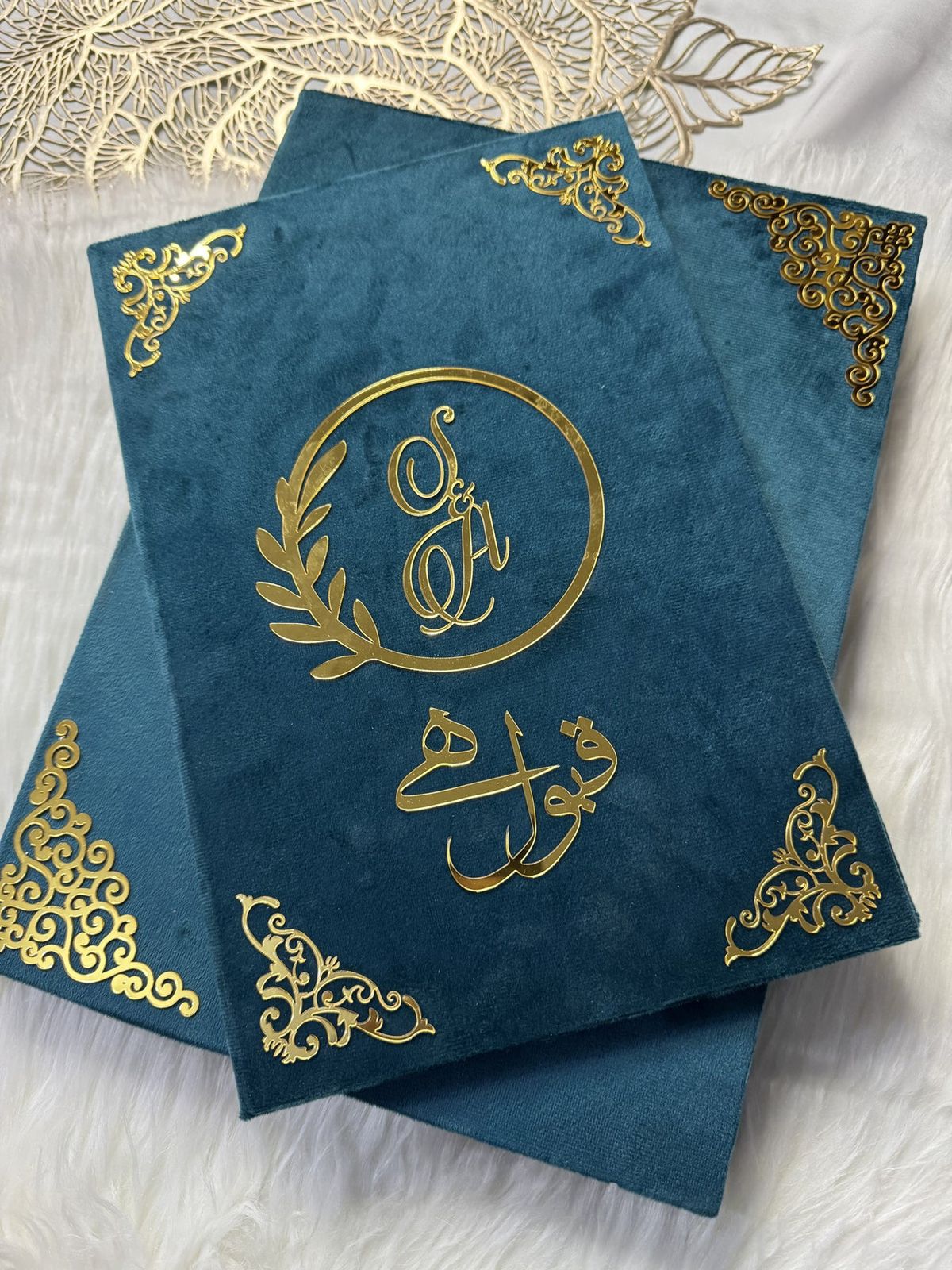 Personalized Nikkah Nama marriage certificate with intricate gold Islamic borders, Arabic calligraphy, and traditional bride-and-groom illustration inside a luxury teal blue folder.