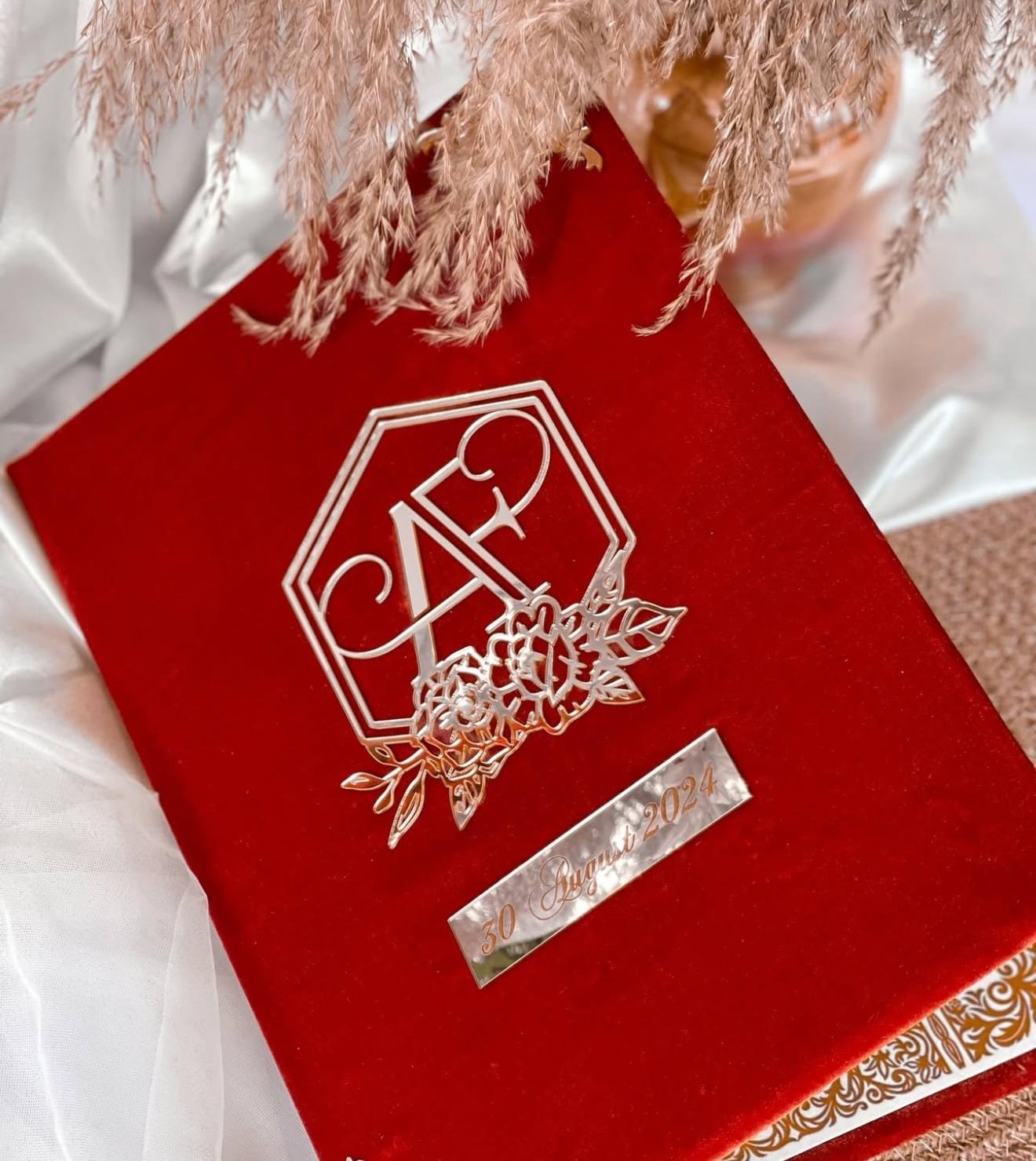 Personalized red velvet Nikkah Nama folder featuring a silver-toned floral monogram with couple's initials and a custom wedding date plaque for Pakistani Muslim wedding ceremonies in the USA.
