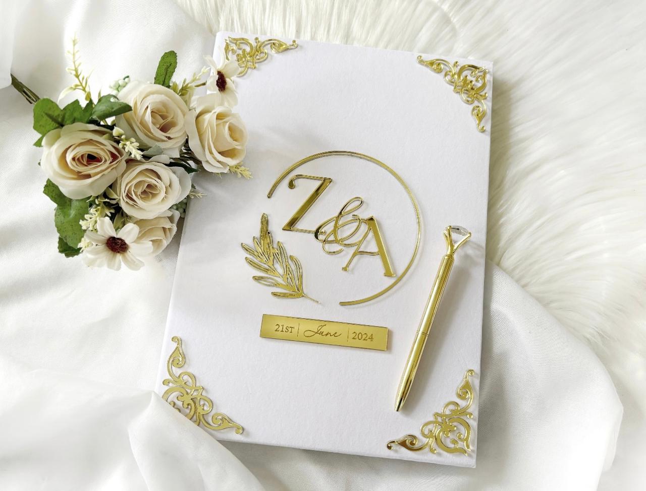 Personalized white Nikkah Nama folder with elegant gold floral monogram, custom couple initials, wedding date plaque, and intricate gold corner embellishments for Pakistani and Muslim wedding ceremonies in the USA.