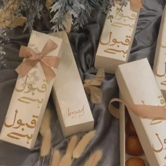 Ivory Qabool Hai Mithai Favor Boxes with gold Urdu calligraphy and satin bows for Pakistani Nikkah and Muslim wedding celebrations.